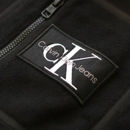 Calvin Klein Jeans logo patch on a black fleece garment