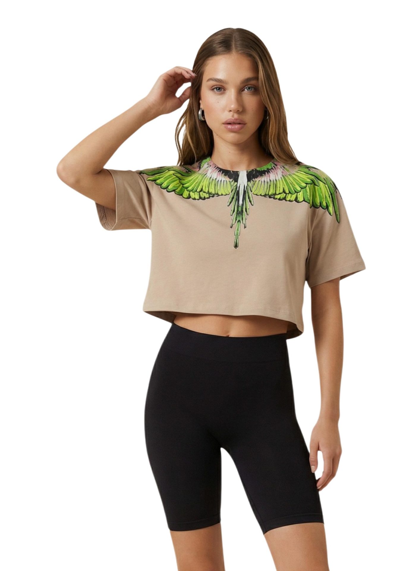Model wearing a beige cropped t-shirt with a green wing print around the collar, paired with black biker shorts