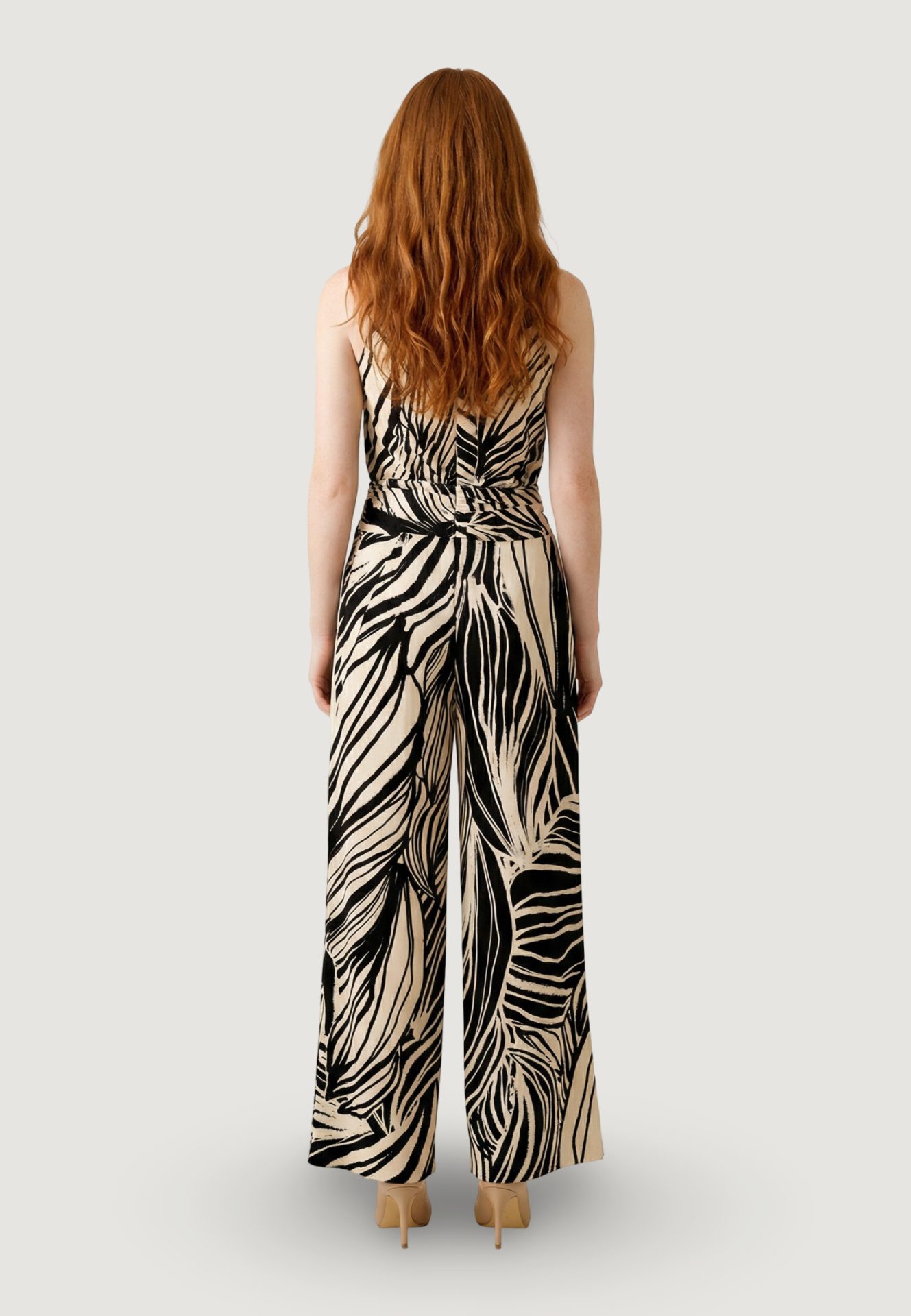 Back view of a sleeveless wide-leg jumpsuit in a black and beige abstract print
