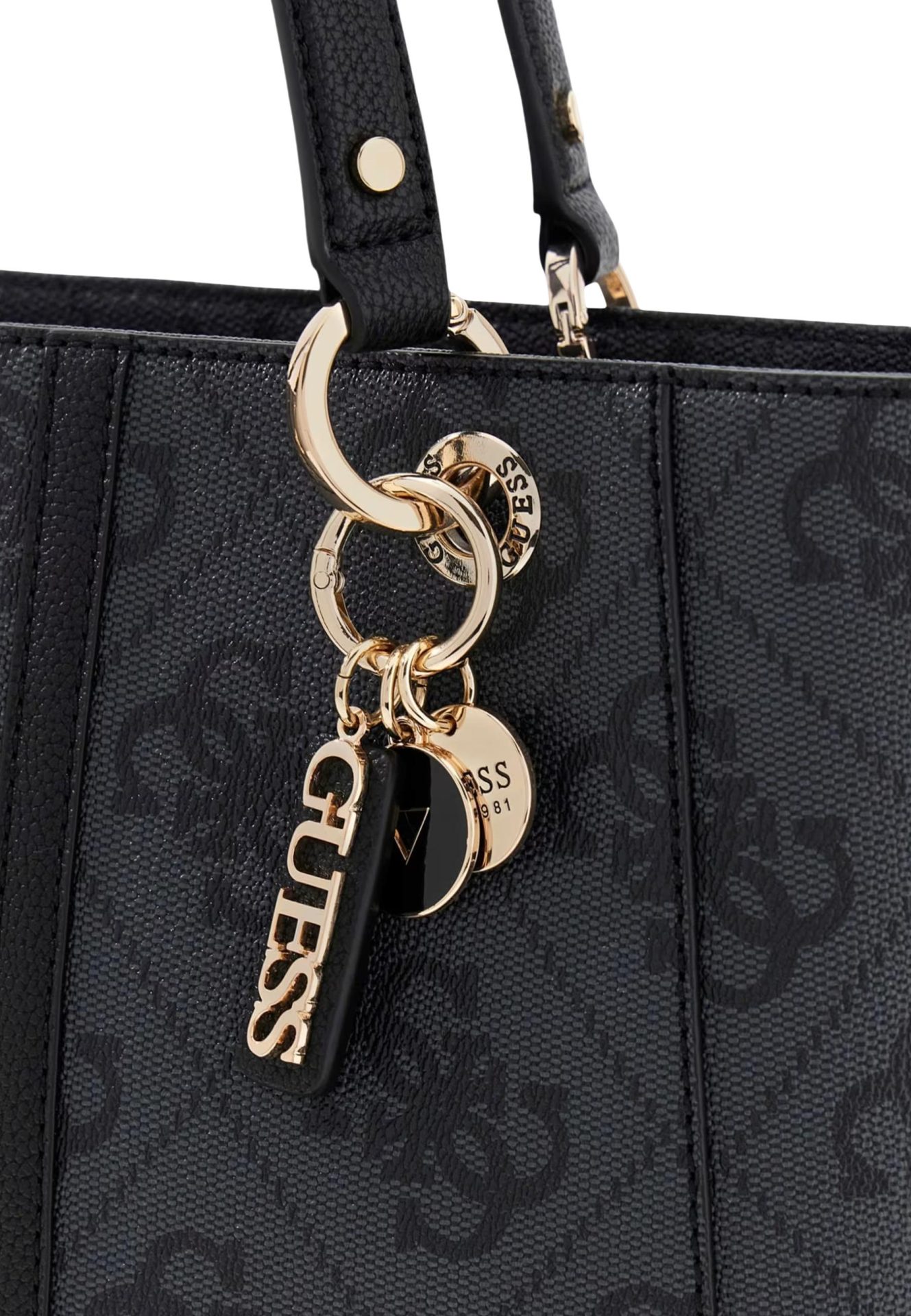 Close-up of a black textured Guess handbag featuring gold-tone logo charms attached to the handle