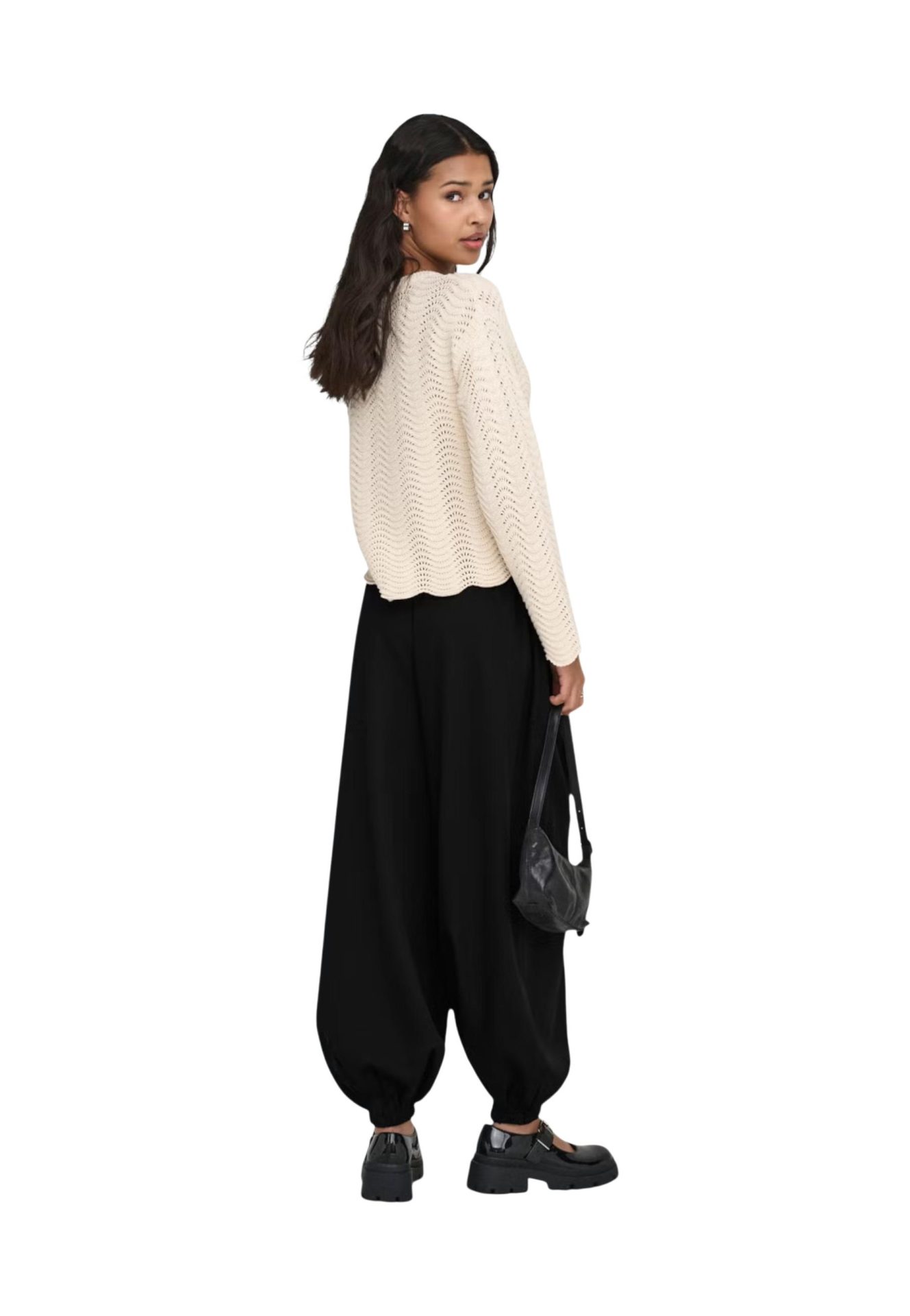 Woman wearing a cream textured knit long-sleeve top, loose black harem pants, and black platform shoes