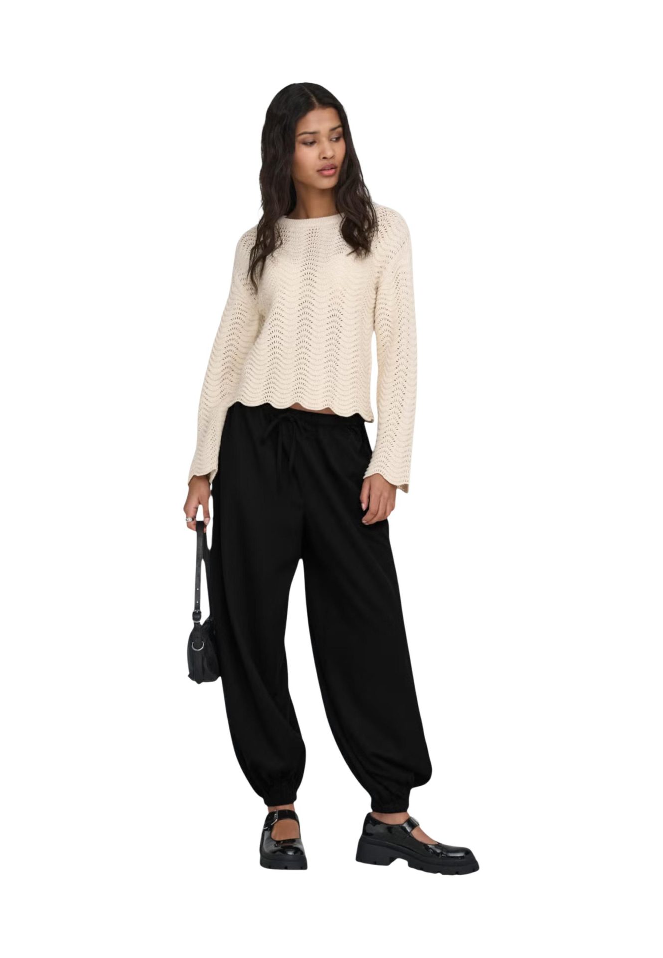 Model wearing a cream-colored textured knit sweater, black loose-fitting jogger pants, and black platform shoes